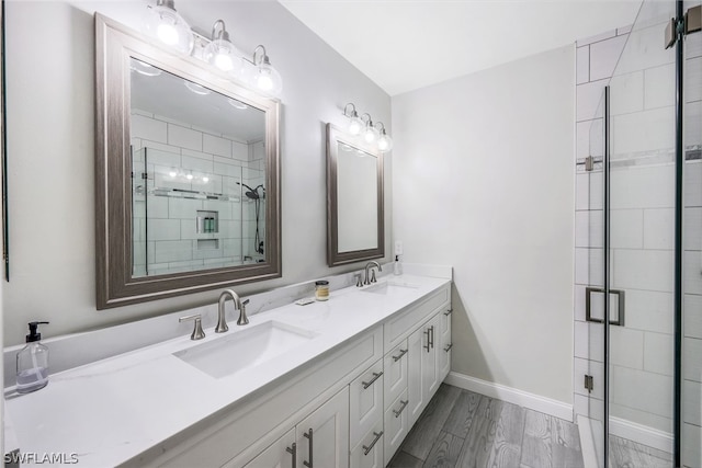 full bath featuring double vanity, baseboards, a stall shower, and a sink