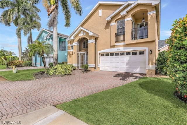 mediterranean / spanish house featuring stucco siding, a front lawn, decorative driveway, an attached garage, and a balcony