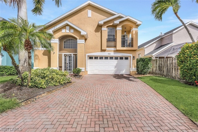 view of front of property with a balcony, fence, stucco siding, a garage, and decorative driveway