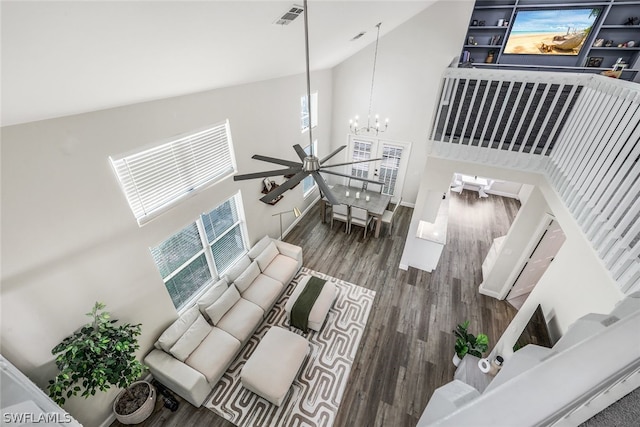 living room with ceiling fan with notable chandelier, high vaulted ceiling, and dark hardwood / wood-style flooring