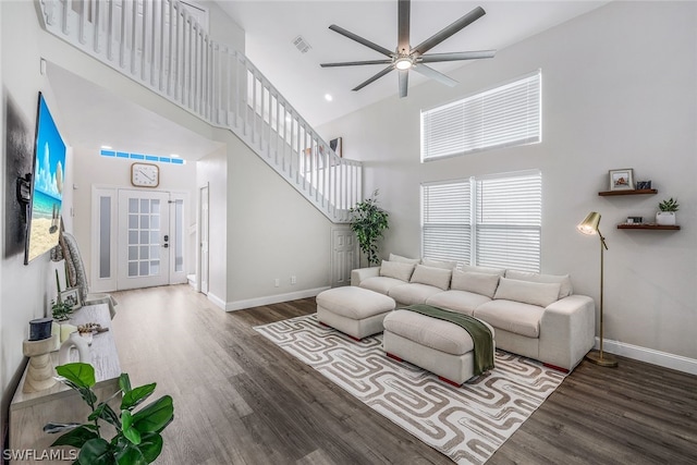 living room with a towering ceiling, ceiling fan, and dark hardwood / wood-style floors