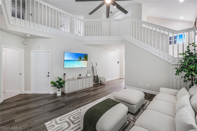 living area with recessed lighting, baseboards, dark wood finished floors, and a towering ceiling