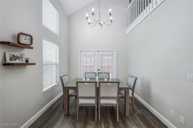 dining space featuring a towering ceiling, an inviting chandelier, french doors, and dark hardwood / wood-style floors