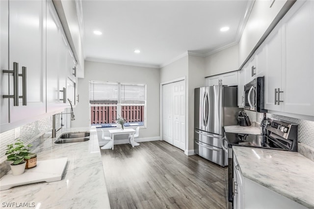 kitchen featuring sink, white cabinets, light stone counters, hardwood / wood-style flooring, and appliances with stainless steel finishes