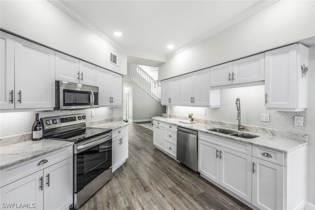 kitchen featuring visible vents, a sink, stainless steel appliances, white cabinetry, and crown molding