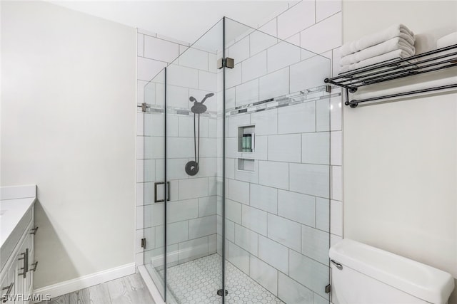 full bath featuring toilet, a stall shower, vanity, and baseboards