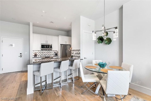 kitchen featuring white cabinetry, light hardwood / wood-style flooring, kitchen peninsula, decorative backsplash, and appliances with stainless steel finishes