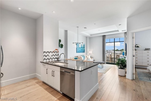 kitchen with kitchen peninsula, stainless steel dishwasher, pendant lighting, white cabinets, and sink