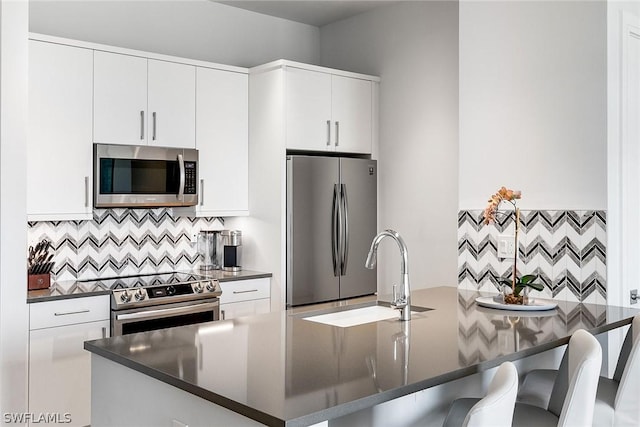 kitchen featuring sink, white cabinetry, a kitchen breakfast bar, tasteful backsplash, and appliances with stainless steel finishes