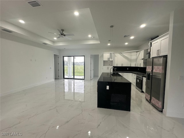 kitchen with sink, appliances with stainless steel finishes, white cabinetry, and an island with sink