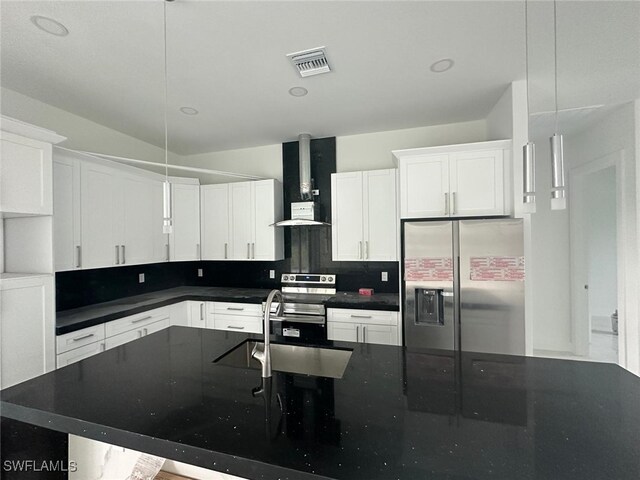 kitchen featuring white cabinetry, sink, wall chimney exhaust hood, decorative light fixtures, and stainless steel appliances