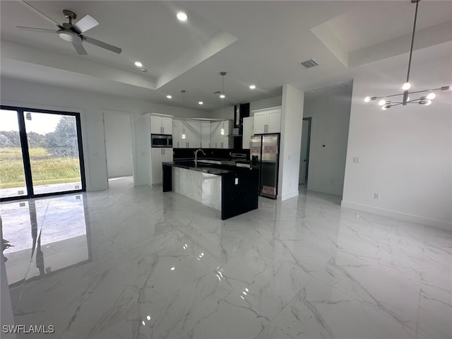 kitchen featuring appliances with stainless steel finishes, white cabinetry, a center island with sink, and pendant lighting