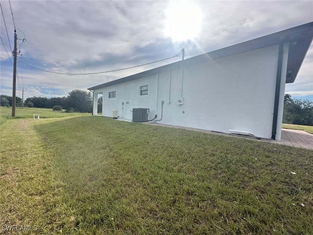 view of side of property with a yard and central air condition unit