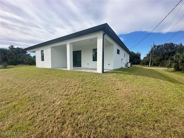 rear view of property with central air condition unit and a lawn