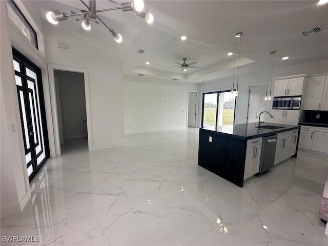 kitchen featuring an island with sink, sink, white cabinets, pendant lighting, and appliances with stainless steel finishes