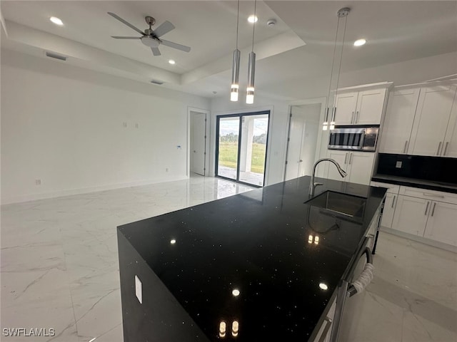 kitchen with sink, white cabinetry, pendant lighting, and a raised ceiling