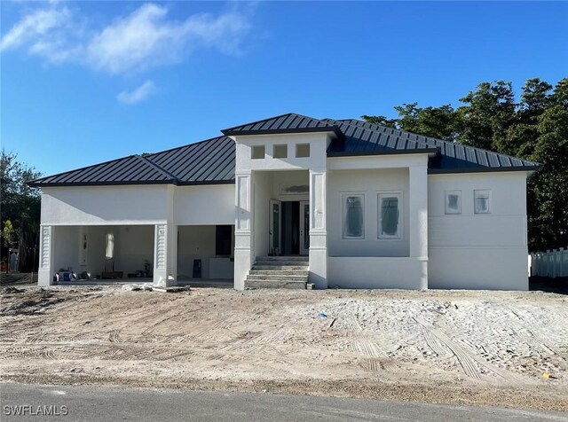 view of front of house featuring stucco siding, metal roof, and a standing seam roof