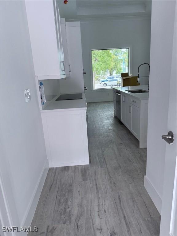 clothes washing area featuring light wood-type flooring, a sink, and baseboards