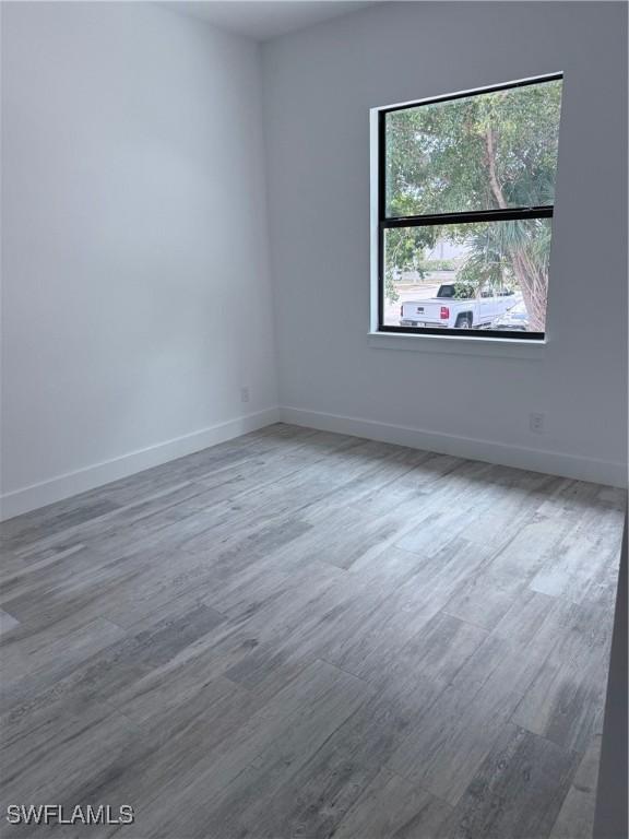 unfurnished room with baseboards and wood finished floors