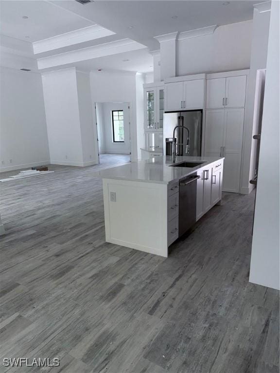 kitchen with wood finished floors, open floor plan, white cabinetry, a sink, and stainless steel appliances