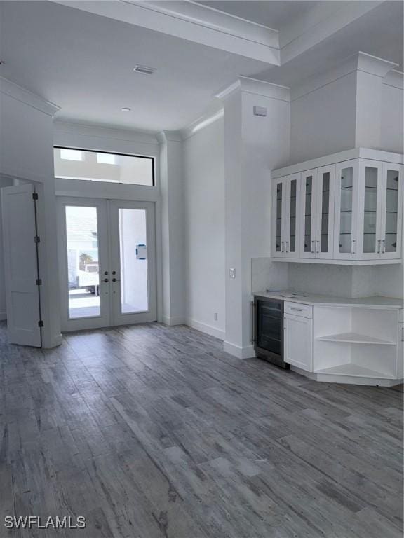 unfurnished living room featuring crown molding, baseboards, french doors, and wood finished floors