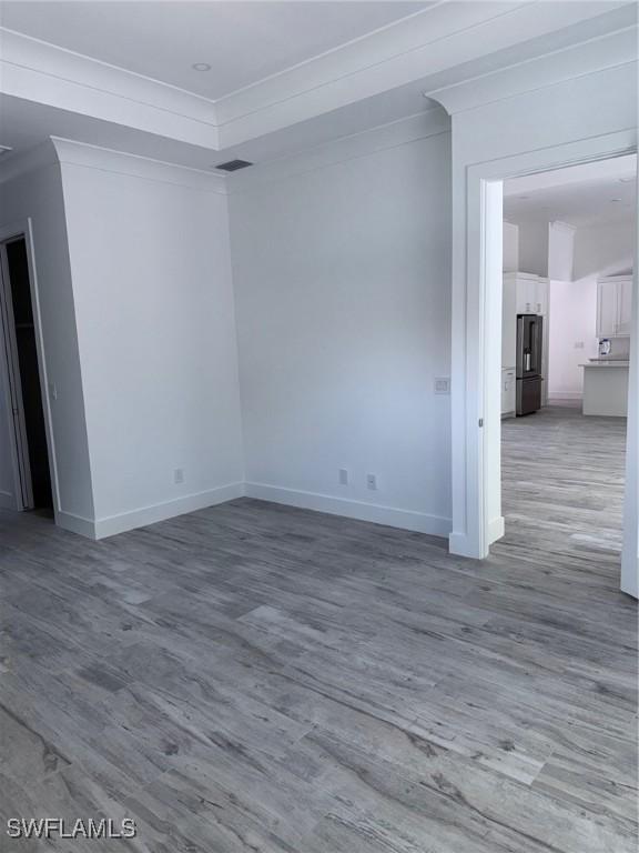 empty room with baseboards, ornamental molding, and wood finished floors