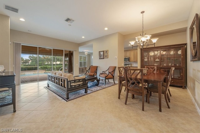 tiled dining area with ceiling fan with notable chandelier