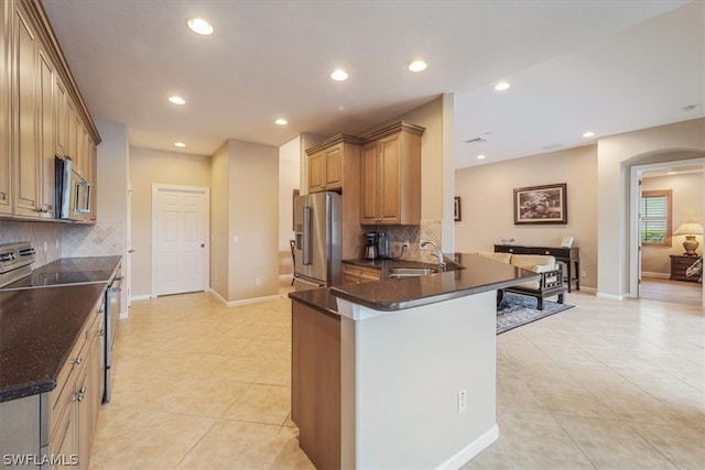 kitchen with sink, appliances with stainless steel finishes, kitchen peninsula, and backsplash