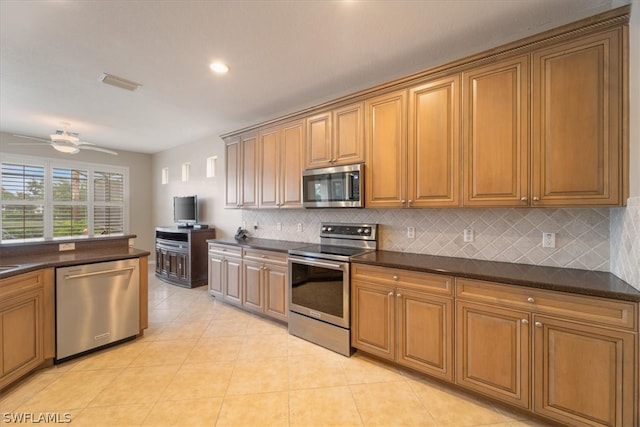 kitchen with light tile patterned floors, dark stone counters, backsplash, ceiling fan, and stainless steel appliances