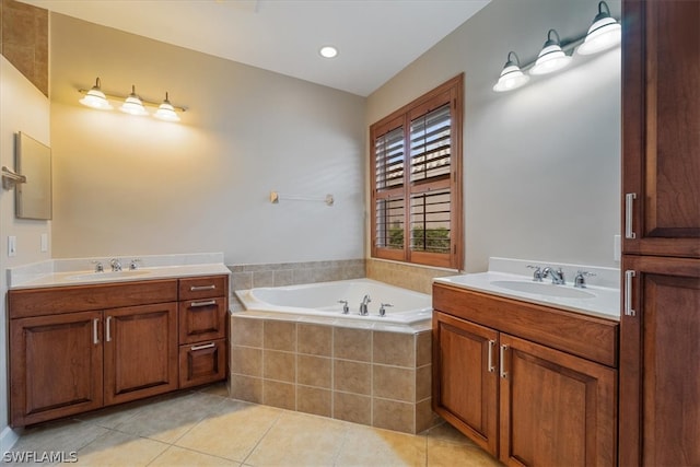 bathroom featuring tile patterned flooring, tiled bath, and vanity