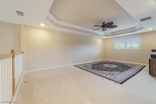 interior space featuring crown molding, a raised ceiling, light colored carpet, and ceiling fan