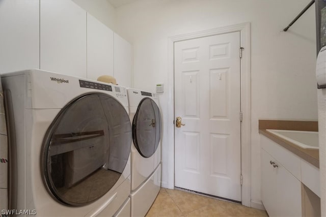 laundry area with independent washer and dryer, cabinets, and light tile patterned floors