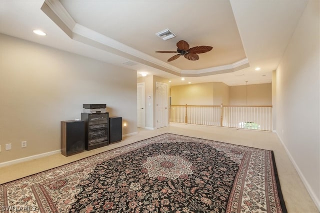 interior space featuring carpet, ceiling fan, crown molding, and a tray ceiling