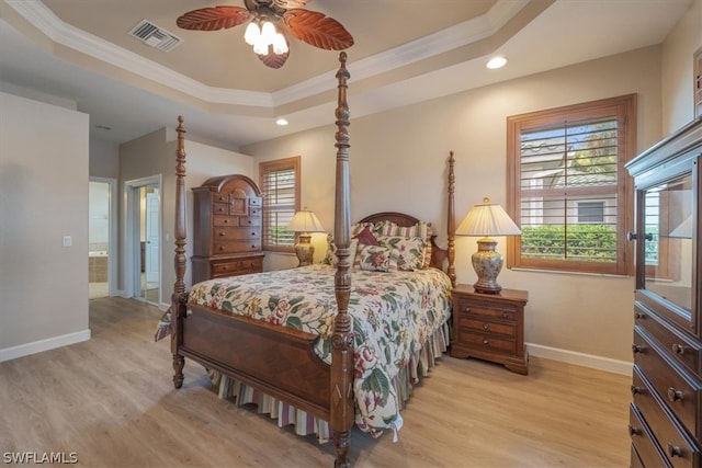 bedroom with ceiling fan, ensuite bathroom, a tray ceiling, and light hardwood / wood-style floors