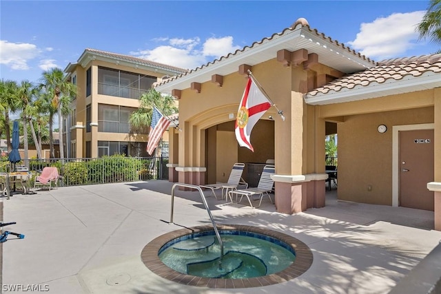 rear view of property featuring a community hot tub and a patio