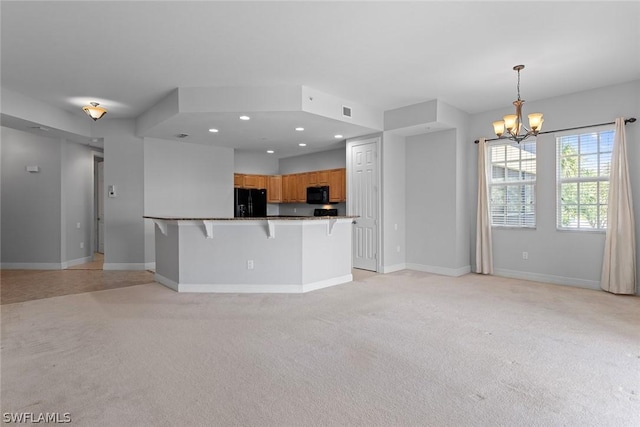 kitchen with an inviting chandelier, kitchen peninsula, a breakfast bar area, light carpet, and black appliances