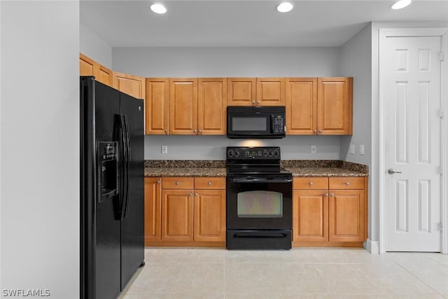 kitchen with light tile patterned floors, dark stone countertops, and black appliances