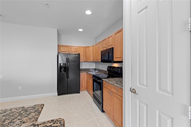 kitchen featuring light tile patterned flooring, dark stone counters, and black appliances