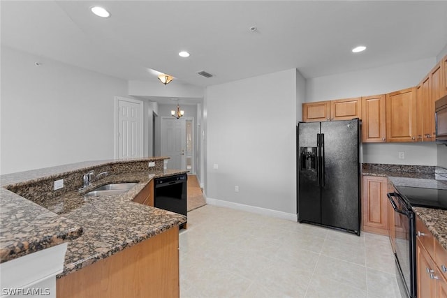 kitchen with dark stone countertops, sink, black appliances, and a notable chandelier