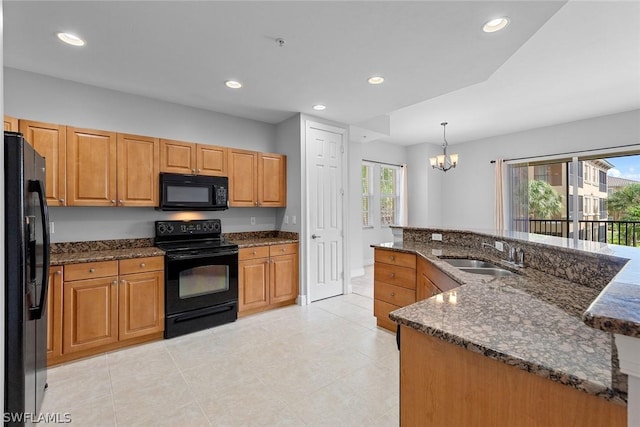 kitchen with black appliances, sink, hanging light fixtures, dark stone countertops, and a notable chandelier