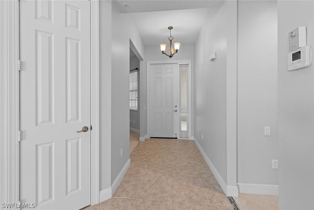 hallway featuring a notable chandelier and light tile patterned floors