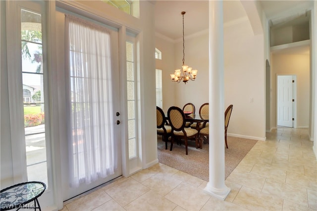 entryway with light tile patterned flooring, an inviting chandelier, crown molding, and plenty of natural light