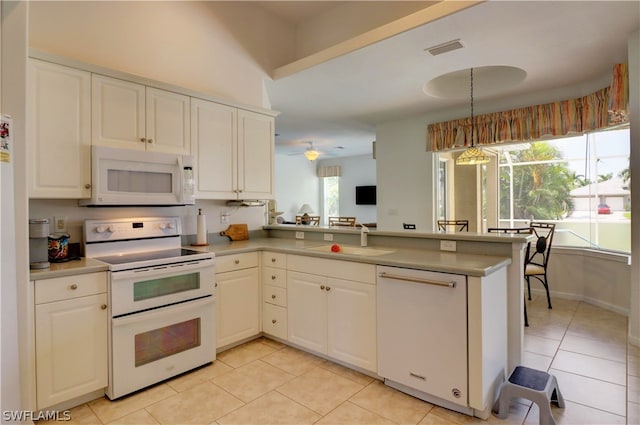 kitchen with a wealth of natural light, kitchen peninsula, and white appliances