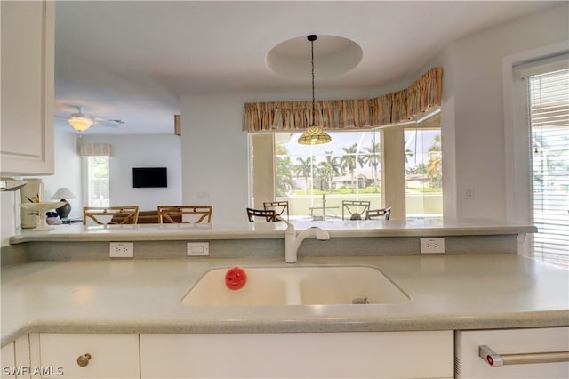 kitchen featuring white cabinets, a healthy amount of sunlight, hanging light fixtures, and sink