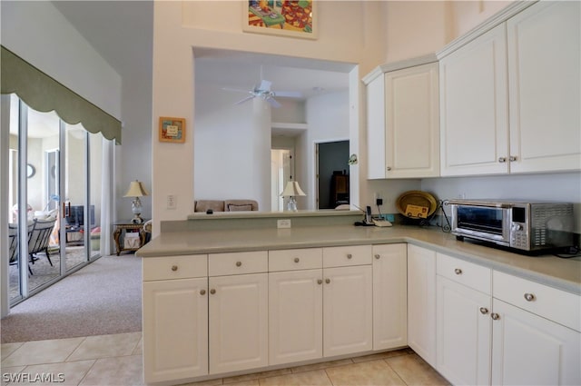 kitchen with kitchen peninsula, white cabinetry, light tile patterned floors, and ceiling fan