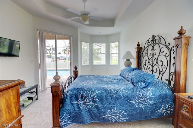 carpeted bedroom with a tray ceiling, access to outside, and ceiling fan