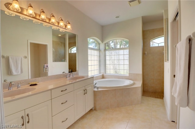 bathroom with tiled tub, tile patterned floors, and double sink vanity