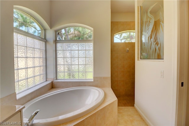 bathroom with tiled tub and tile patterned floors