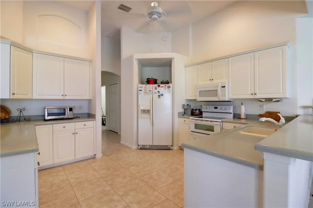 kitchen with ceiling fan, white appliances, sink, light tile patterned floors, and a towering ceiling