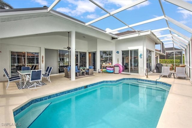 view of swimming pool with ceiling fan, glass enclosure, and a patio